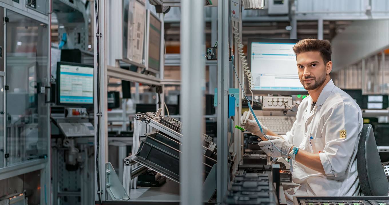 Young worker at electronics pcb production for smart keys at huf automotive supplier